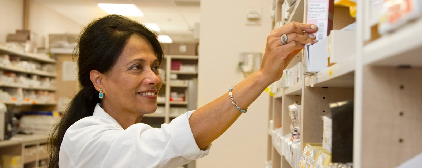 A clinician reaching for medication on a dispensary shelf